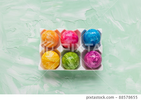 Multicolored six Easter eggs in porcelain storage organizer box on green background 88578655
