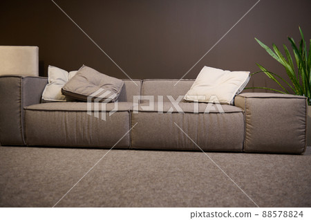 Front view of a large comfortable sofa made of high quality fabrics and soft cushions, on display for sale in the showroom of a furniture store. Home interior design, living room decoration Front view of a large comfortable sofa made of high quality fabrics and soft cushions, on display for sale in the showroom of a furniture store. Home interior design, living room decoration 88578824