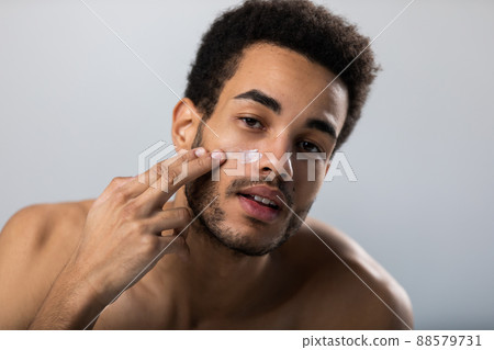 Attractive man doing facial beauty treatments. 88579731