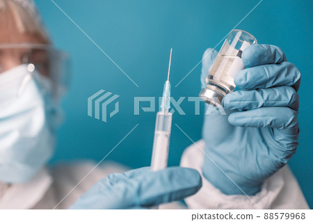Close up of doctor or nurse holding viol with vaccine against corona virus, taking covid vaccination booster shot or 3rd dose from syringe. Close up of doctor or nurse holding viol with vaccine against corona virus, taking covid vaccination booster shot or 3rd dose from syringe. 88579968