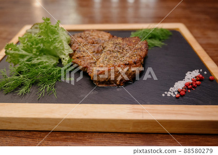A juicy piece of fried meat lies on a cutting board against a wooden table. A juicy piece of fried meat lies on a cutting board against a wooden table. 88580279