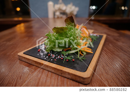 A juicy piece of fried meat lies on a cutting board against a wooden table. 88580282