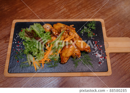 A juicy piece of fried meat lies on a cutting board against a wooden table. A juicy piece of fried meat lies on a cutting board against a wooden table. 88580285
