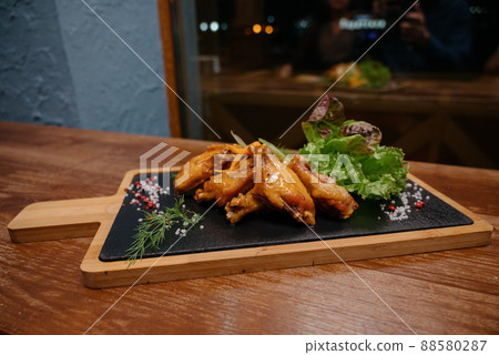 A juicy piece of fried meat lies on a cutting board against a wooden table. A juicy piece of fried meat lies on a cutting board against a wooden table. 88580287