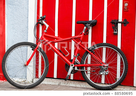 Red bycicle next to a red door at the beautiful small town of Filandia in the region of Quindio in Colombia 88580695