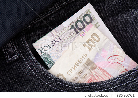 Ukrainian hryvnia and Polish zloty protrude from the pocket of jeans close-up. Ukrainian hryvnia and Polish zloty protrude from the pocket of jeans close-up. 88580761