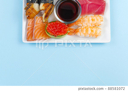 traditional japanese sushi set on a white plate isolated on a blue background. tasty set of sushi, nigiri, sahimi and maki. delicious dinner or lunch for one person. flat lay traditional japanese sushi set on a white plate isolated on a blue background. tasty set of sushi, nigiri, sahimi and maki. delicious dinner or lunch for one person. flat lay 88581072