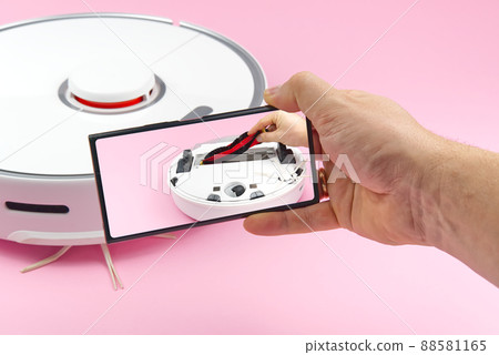 white robot vacuum cleaner on a pink background. The procedure for cleaning the robot vacuum cleaner after cleaning. future home technology. white robot vacuum cleaner on a pink background. The procedure for cleaning the robot vacuum cleaner after cleaning. future home technology. 88581165
