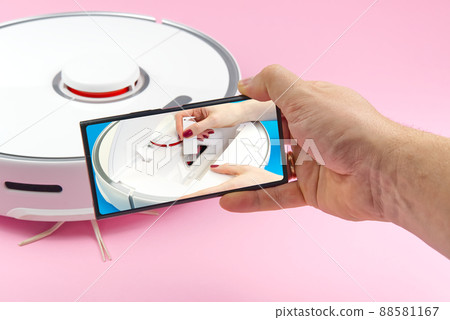 white robot vacuum cleaner on a pink background. The procedure for cleaning the robot vacuum cleaner after cleaning. future home technology. white robot vacuum cleaner on a pink background. The procedure for cleaning the robot vacuum cleaner after cleaning. future home technology. 88581167