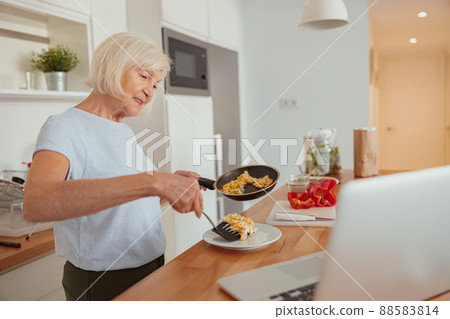Happy senior woman preparing healthy lunch at home Happy senior woman preparing healthy lunch at home 88583814