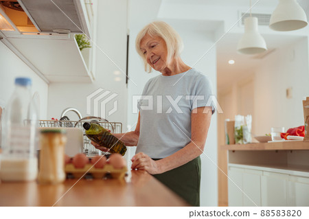 Pension age good looking woman cooking food indoors Pension age good looking woman cooking food indoors 88583820