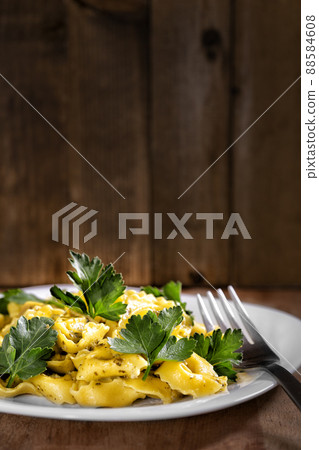 Ravioli with fresh parsley leaves on wooden rustic surface. Traditional italian kitchen cuisine. 88584608