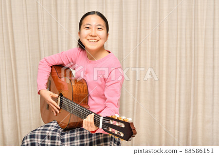 A girl playing an acoustic guitar A girl playing an acoustic guitar 88586151