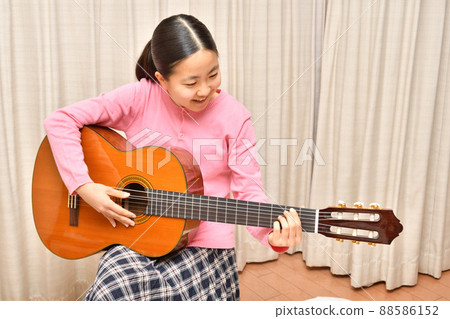 A girl playing an acoustic guitar A girl playing an acoustic guitar 88586152