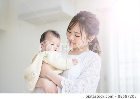 Mom hugging her baby in a bright living room 88587205