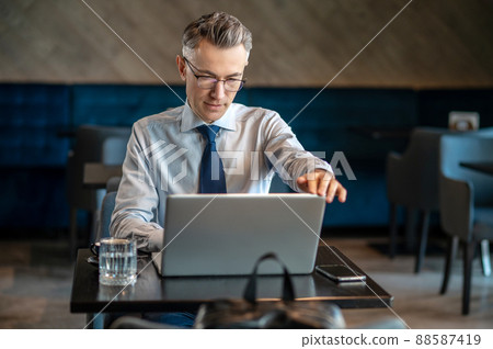 A businessman working on a laptop in a cafe A businessman working on a laptop in a cafe 88587419
