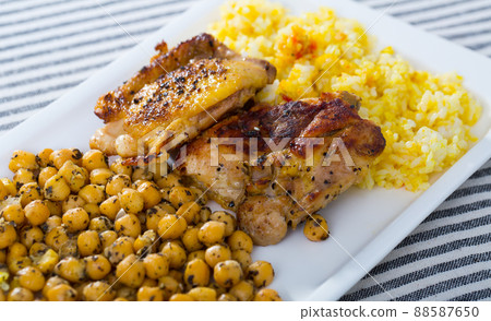 Grilled chicken thighs with garbanzo and yellow rice at plate 88587650