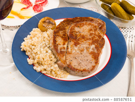 Barley groats with frying beef loin at plate on table, nobody 88587651
