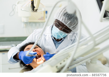 Male dentist using tools for tooth repairing on woman patient 88587736