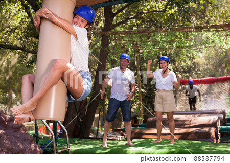 Friends help each other overcome water obstacles in theme park Friends help each other overcome water obstacles in theme park 88587794