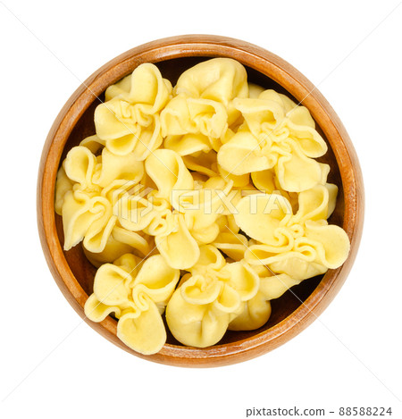 Boiled fagottini, Italian pasta, in a wooden bowl. Typically shaped dumplings, made by cutting pasta dough into squares, placing the filling in the center, and folding the corners, to meet in a point. 88588224