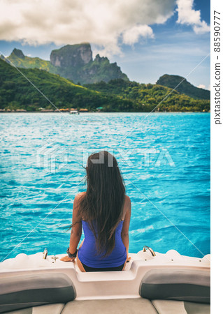 Luxury travel boat trip excursion woman tourist relaxing on idyllic blue lagoon cruise vacation travel holiday in Bora Bora island, Tahiti, French Polynesia. Girl from behind with long hair Luxury travel boat trip excursion woman tourist relaxing on idyllic blue lagoon cruise vacation travel holiday in Bora Bora island, Tahiti, French Polynesia. Girl from behind with long hair 88590777