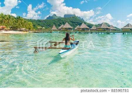 French Polynesia Tahiti travel vacation concept. Outrigger Canoe polynesian watersport sport woman paddling in traditional vaa boat. Water leisure activity, Bora Bora overwater bungalow resort hotel 88590781