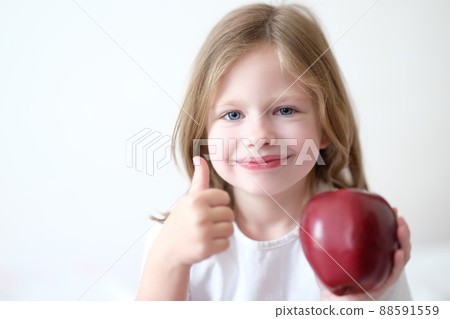 Little girl holding red apple in her hands and showing thumbs up 88591559
