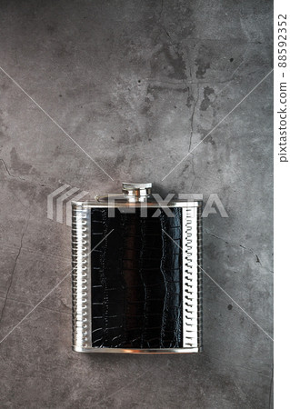 Steel flask in leather finish for alcohol on a dark background with copy space Steel flask in leather finish for alcohol on a dark background with copy space 88592352