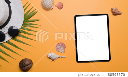 Above view digital tablet, traveler accessories and seashells on yellow background. Travel, summer and holiday concept. Above view digital tablet, traveler accessories and seashells on yellow background. Travel, summer and holiday concept. 88593670