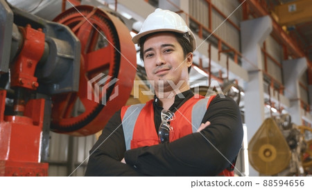 Portrait of young man worker in safety uniform of large modern factory crossing arms on chest 88594656