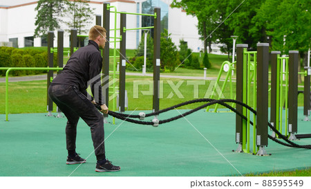 Men with battle rope battle ropes exercise in the street fitness gym. Men with battle rope battle ropes exercise in the street fitness gym. 88595549