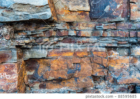 Closeup of dark dged shabby cliff cracks. Gray stone rock texture of mountains. Concept of geology and mountaineering Closeup of dark dged shabby cliff cracks. Gray stone rock texture of mountains. Concept of geology and mountaineering 88595685