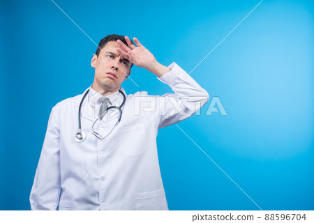Exhausted male doctor touching forehead in studio 88596704