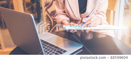 Woman analyzing data graph the stock situation.She uses a pen and a laptop computer. Woman analyzing data graph the stock situation.She uses a pen and a laptop computer. 88599604
