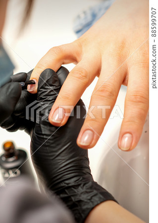 Manicure painting process. Manicure master paint the nails with transparent varnish in a nail salon, close up 88599707