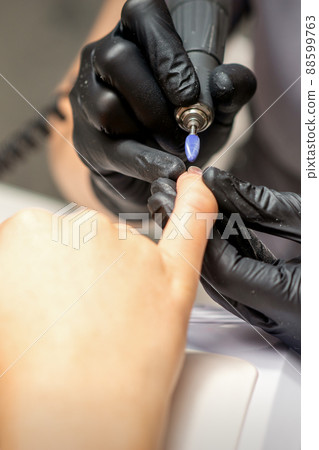 Manicure master uses electric nail file machine in a nail salon, close up Manicure master uses electric nail file machine in a nail salon, close up 88599763