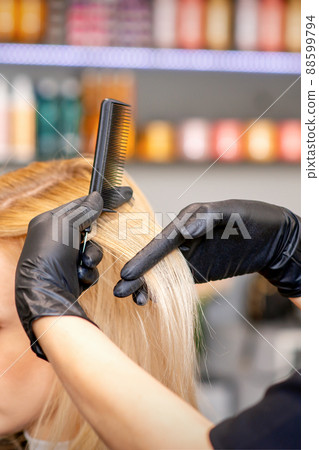 Beautiful young blonde woman with long straight blonde hair getting a haircut at the hairdresser salon 88599794