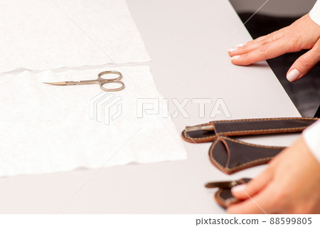 Hands of manicure master prepare nail care tools on a white table Hands of manicure master prepare nail care tools on a white table 88599805