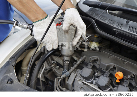 hand of mechanic with wrength torque to tightening bolt in engine at auto service shop ; hand of mechanic with wrength torque to tightening bolt in engine at auto service shop ; 88600235