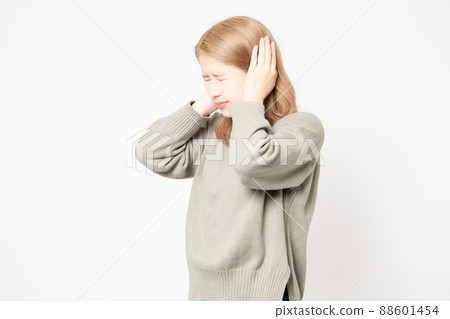Young woman standing in front of a white background and blocking her ears 88601454