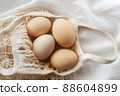 Chicken eggs in a string bag on white background, selective focus. Happy easter background. 88604899