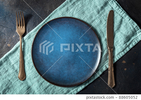 Cutlery with a blue plate. A fork, a knife, and a dish on a teal napkin Cutlery with a blue plate. A fork, a knife, and a dish on a teal napkin 88605052