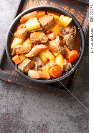 Filipino Menudo is a hearty and tasty pork stew made with fresh tomatoes, potatoes, carrots close up in the plate. Vertical top view Filipino Menudo is a hearty and tasty pork stew made with fresh tomatoes, potatoes, carrots close up in the plate. Vertical top view 88605178