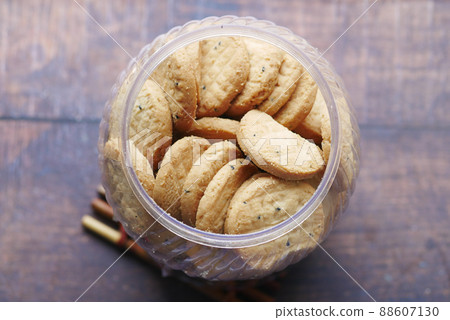 close up of sweet cookies in a plastic jar on wooden table  88607130