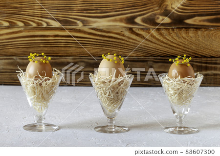 Mimosa decorated eggs in the nests in crystal glasses, idea of Easter decoration 88607300