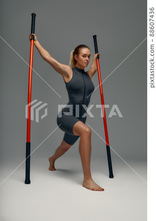beautiful girl in sports uniform is training kung fu in the studio, fighter athlete, practicing martial arts with a stick 88607436