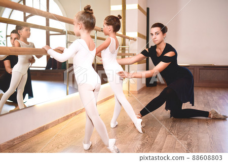 Girls are engaged in choreography in the ballet school.Young ballet teacher and 88608803