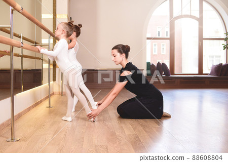 Girls are engaged in choreography in the ballet school.Young ballet teacher and 88608804