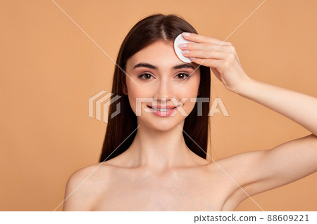 beautiful young woman holding white cotton pad 88609221